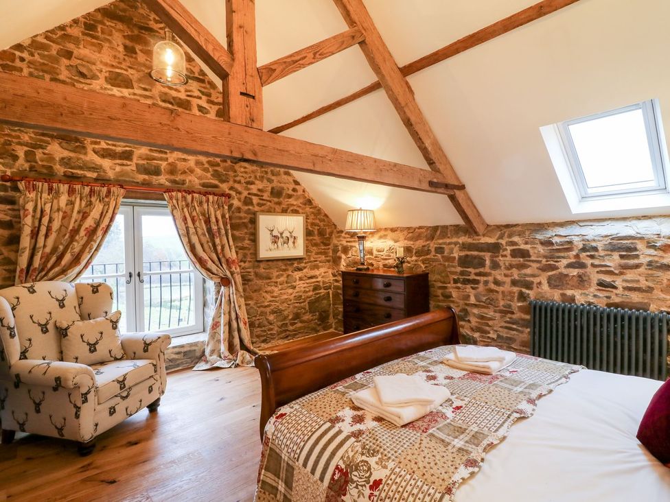 A bedroom with stone walls and wooden beams at Lake View in Crediton