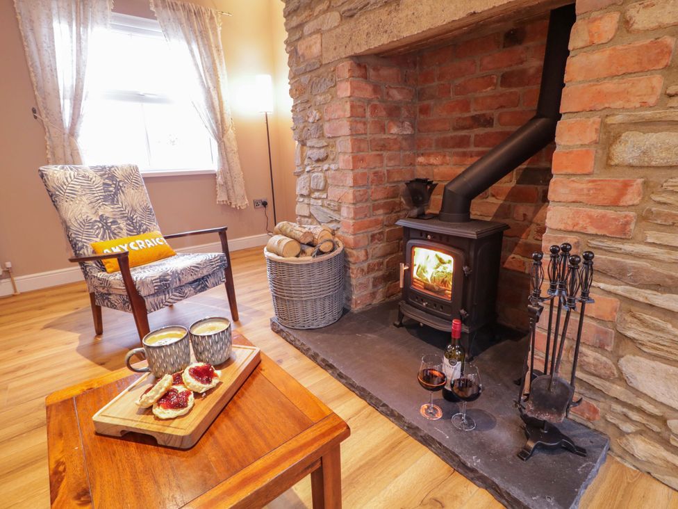 A living room with a fireplace and armchair at Annie’s Farm Cottage