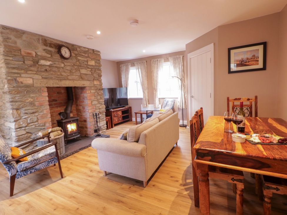 A living room with a fireplace and dining table at Annie’s Farm Cottage
