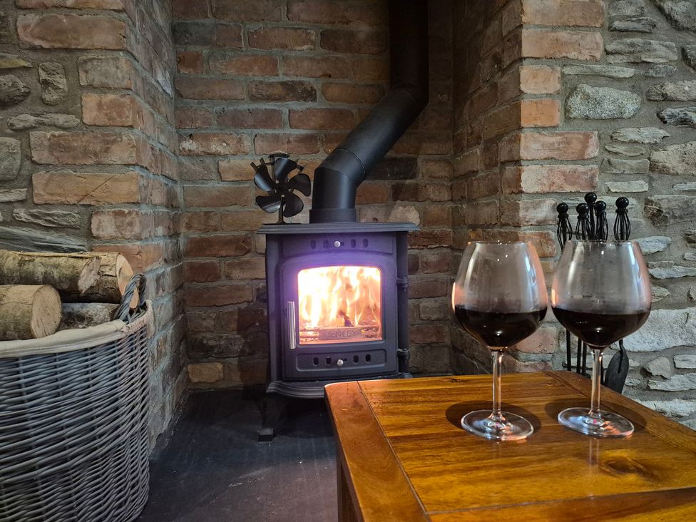 A living room with a fireplace and wine glasses at Annie’s Farm Cottage near Londonderry, Northern Ireland