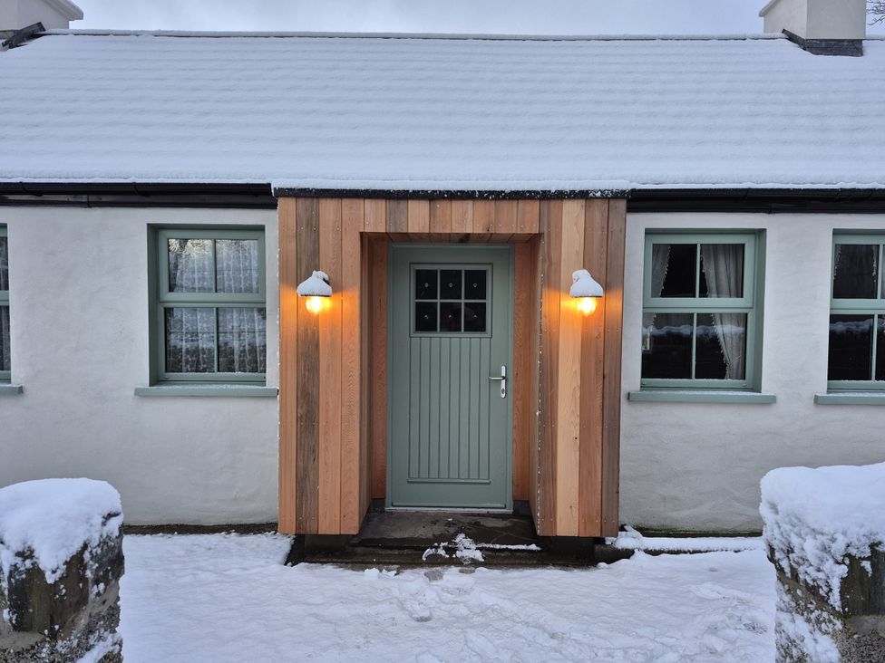 An entrance with a wooden door and windows at Annie’s Farm Cottage near Londonderry, Northern Ireland