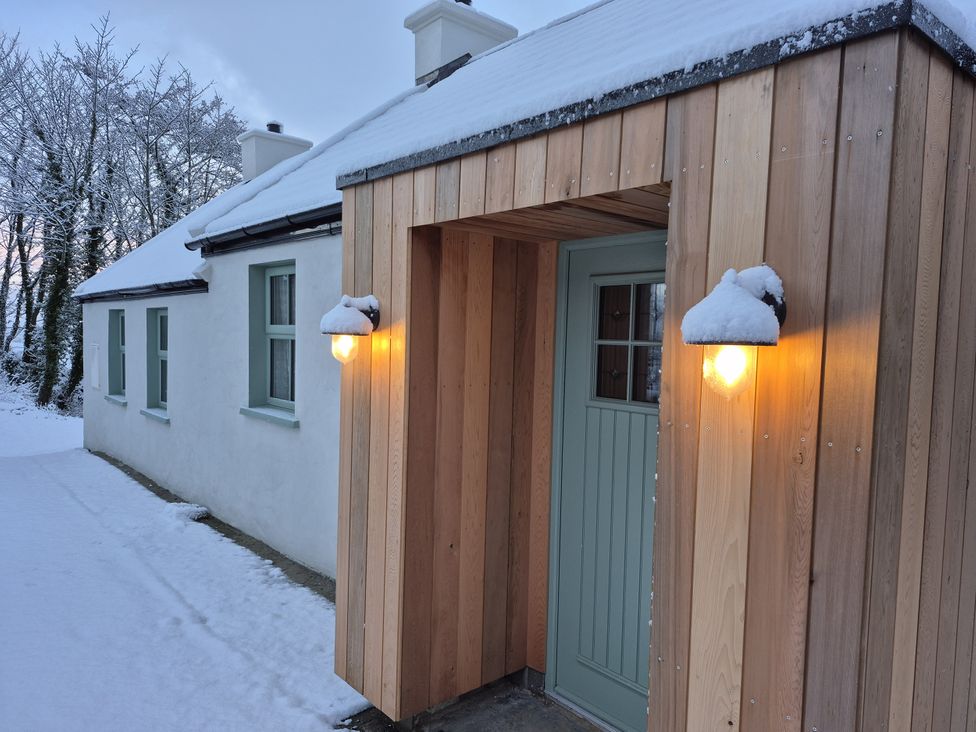 A house entrance with a wooden door and snow at Annie’s Farm Cottage Near Londonderry, Northern Ireland
