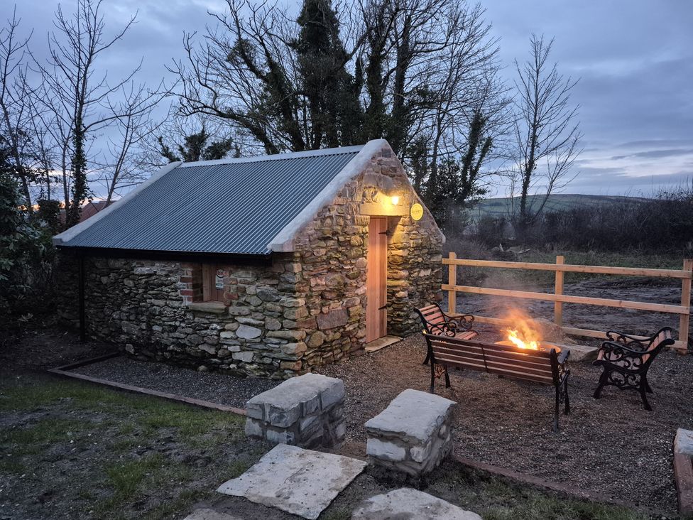 A stone building with a fire pit and benches outside at Annie’s Farm Cottage near Londonderry, Northern Ireland