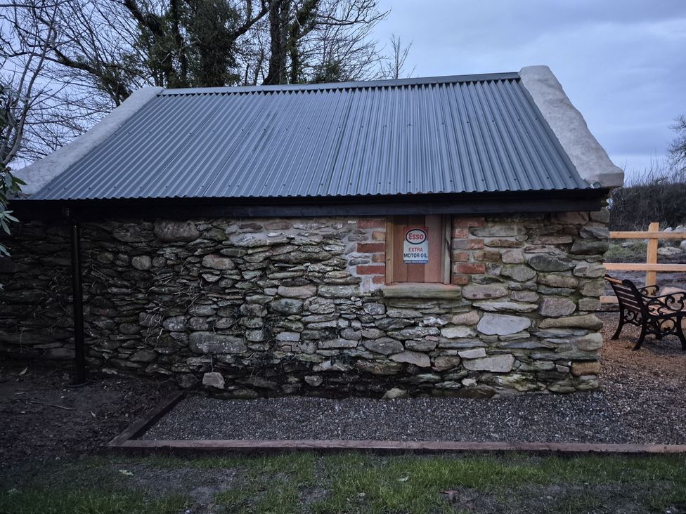 A stone building with a metal roof and a sign at Annie’s Farm Cottage Near Londonderry, Northern Ireland