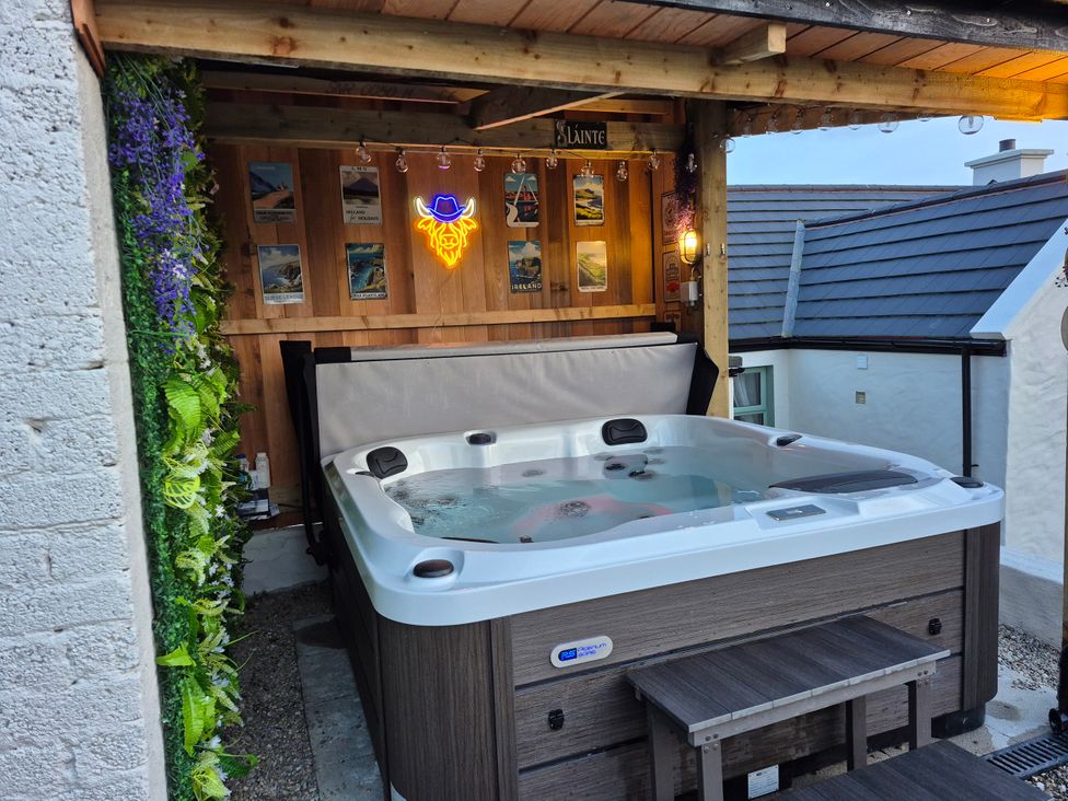 A hot tub in an outdoor area with wooden structure and plant decorations at Annie’s Farm Cottage Near Londonderry, Northern Ireland