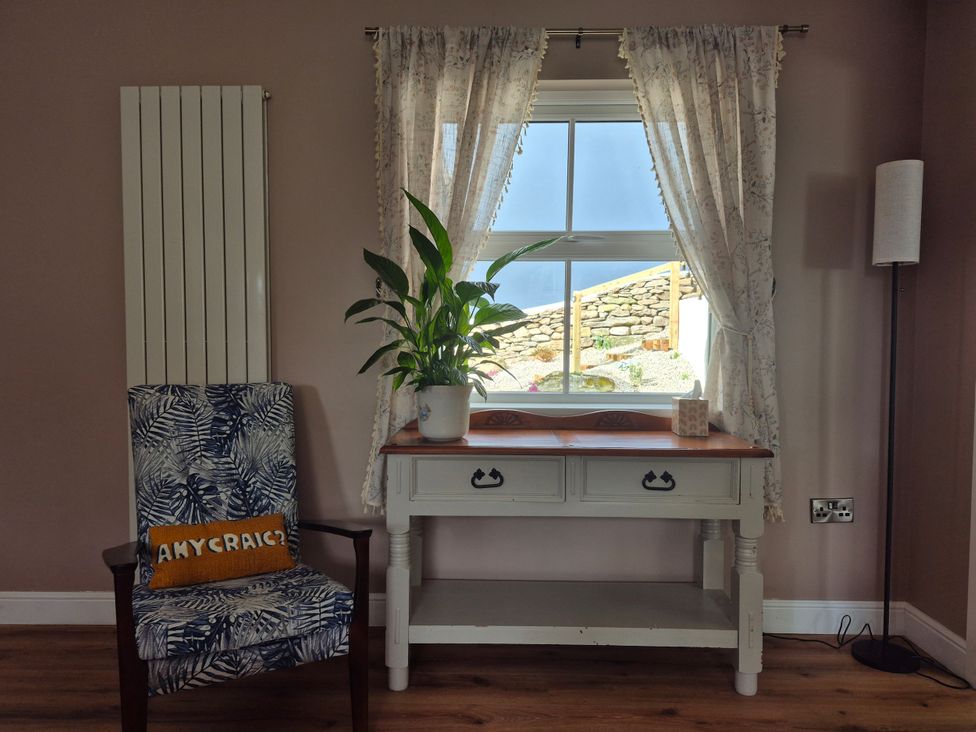 A living room with a chair and table near a window at Annie’s Farm Cottage Near Londonderry, Northern Ireland