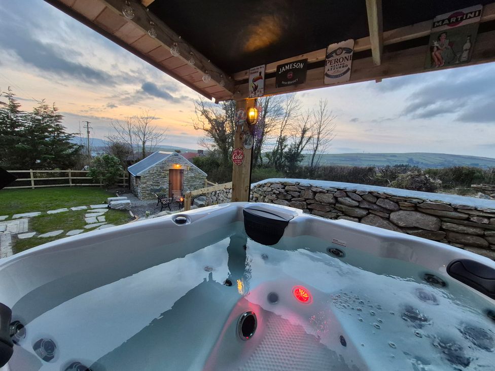 A hot tub in a garden with a stone wall at Annie’s Farm Cottage near Londonderry, Northern Ireland