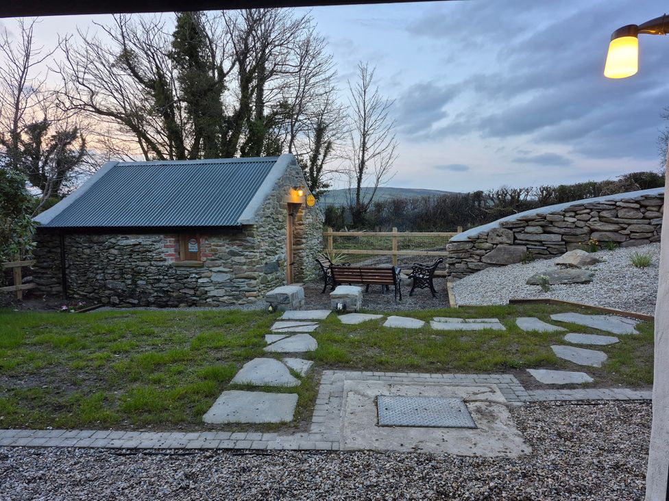 A garden with a stone building and seating area at Annie’s Farm Cottage Near Londonderry, Northern Ireland