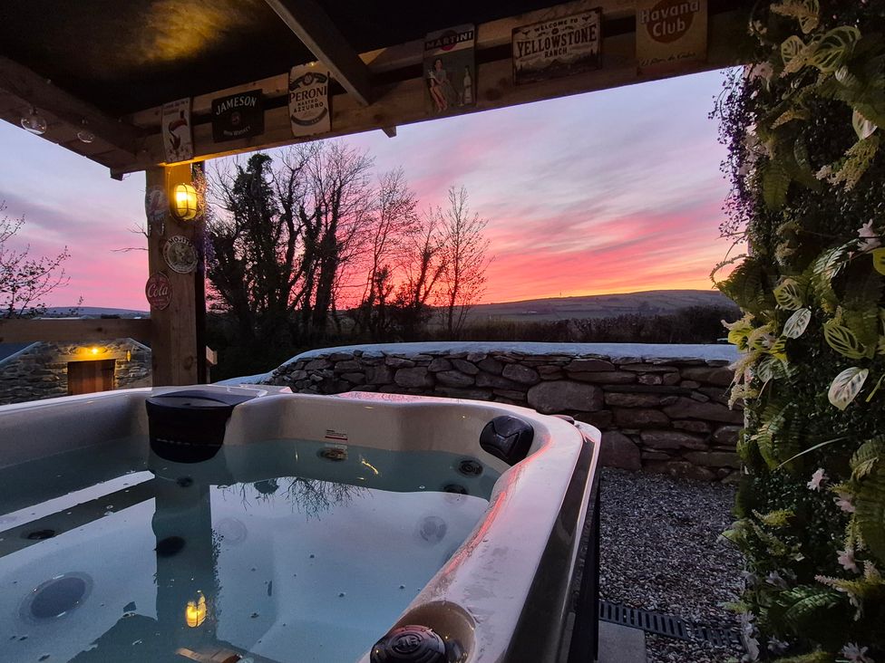 An outdoor area with a hot tub and a view of the sunset at Annie’s Farm Cottage near Londonderry, Northern Ireland