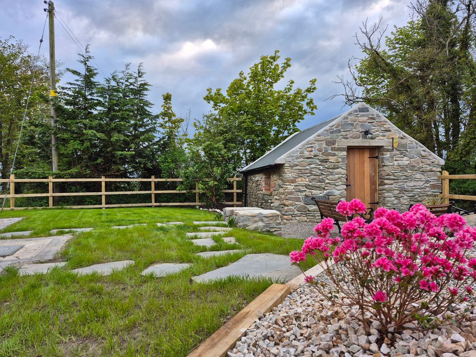 A garden with a stone cottage and flowers at Annie’s Farm Cottage near Londonderry, Northern Ireland