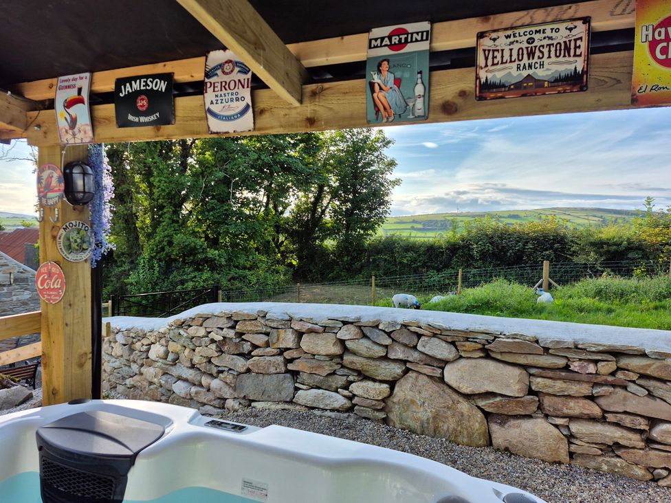 An outdoor area with a hot tub and decorative signs at Annie’s Farm Cottage near Londonderry, Northern Ireland