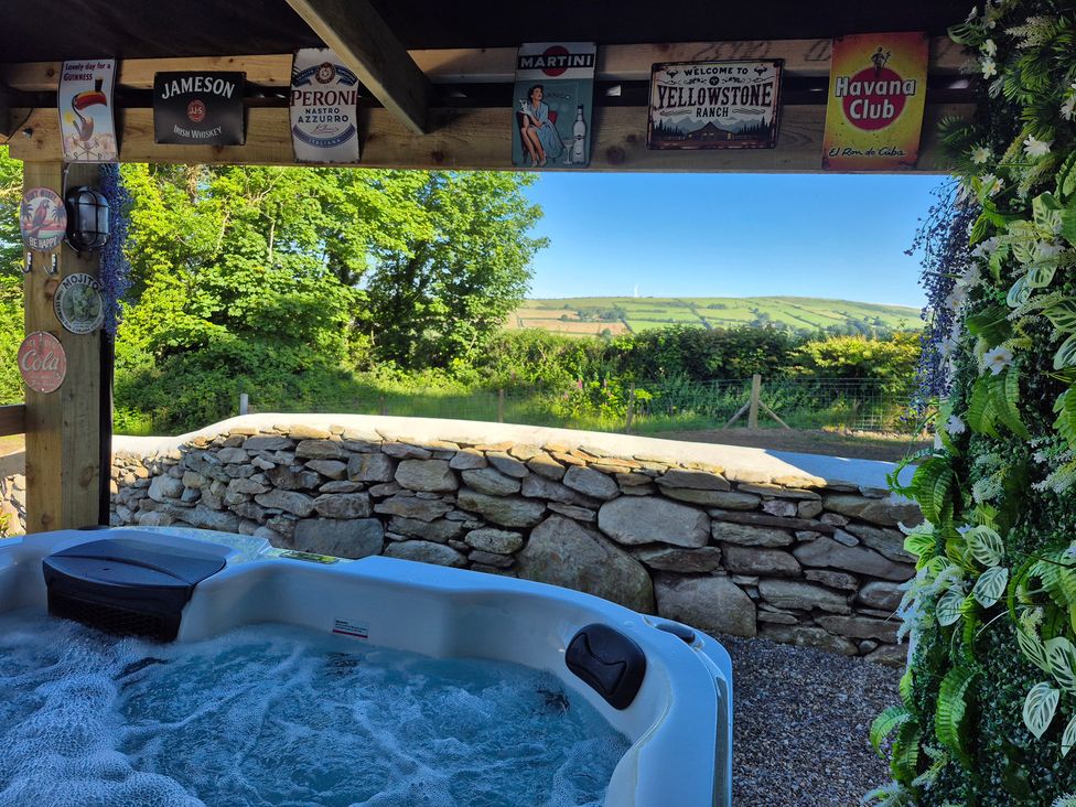 A hot tub beside a stone wall with greenery at Annie’s Farm Cottage Near Londonderry Northern Ireland