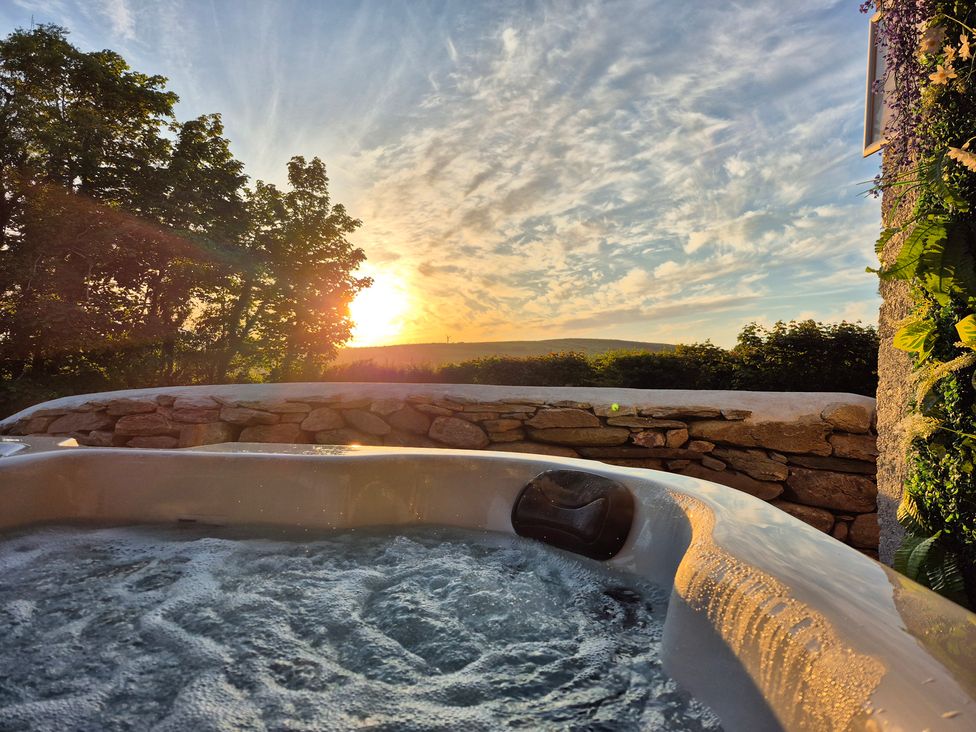 A hot tub with water and a stone wall at Annie’s Farm Cottage Near Londonderry, Northern Ireland