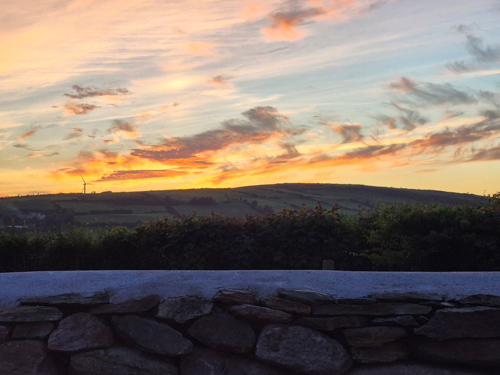 A sunset over hills with a wind turbine at Annie’s Farm Cottage near Londonderry, Northern Ireland