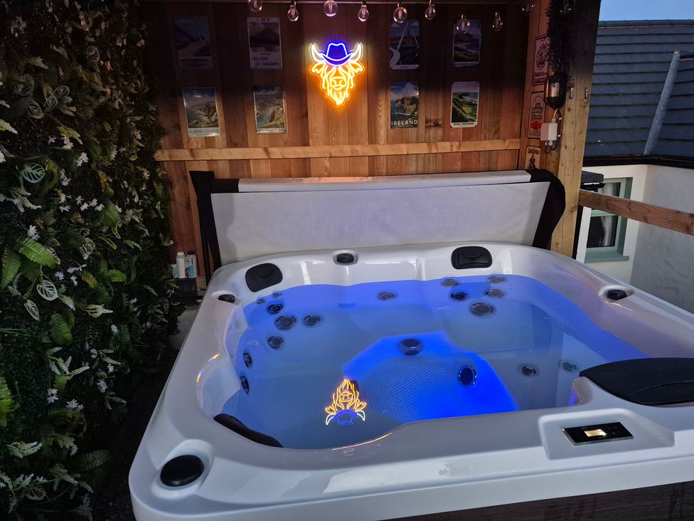 A hot tub with a neon sign and wooden wall near plants at Annie’s Farm Cottage Near Londonderry, Northern Ireland
