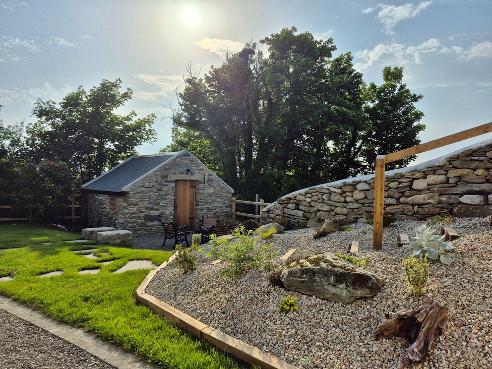 A stone building with chairs and gravel area at Annie’s Farm Cottage near Londonderry, Northern Ireland