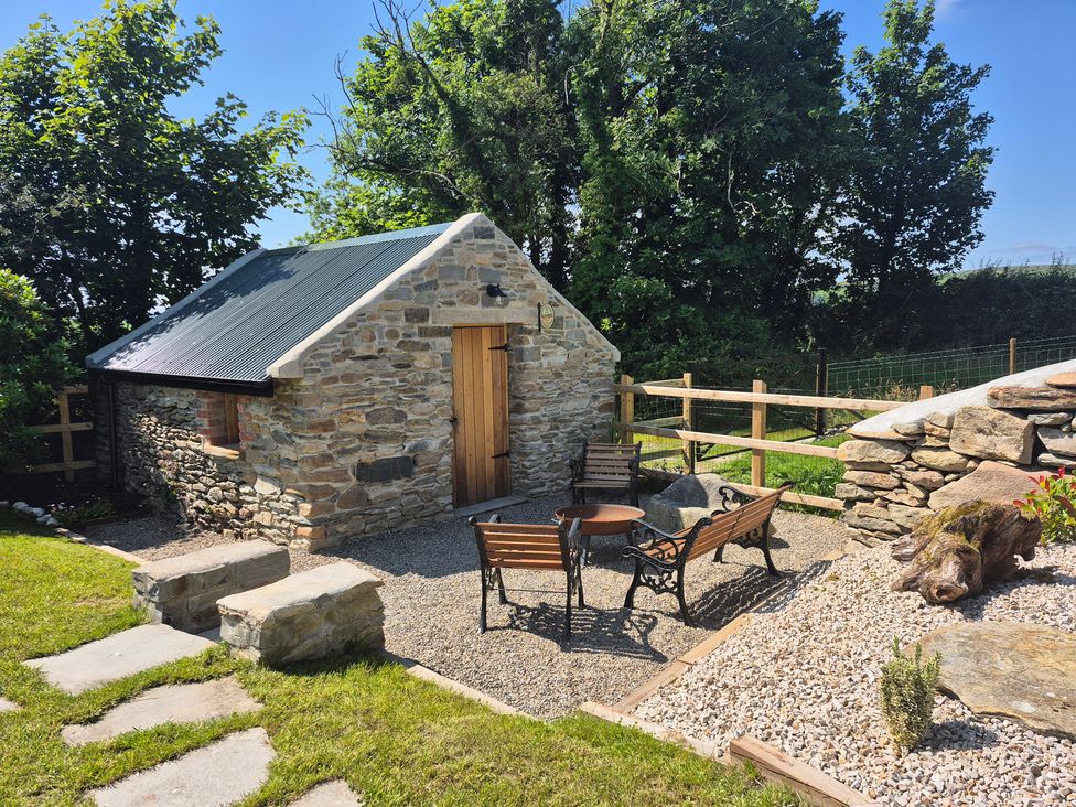 An outdoor area with a stone cottage and seating at Annie’s Farm Cottage near Londonderry, Northern Ireland
