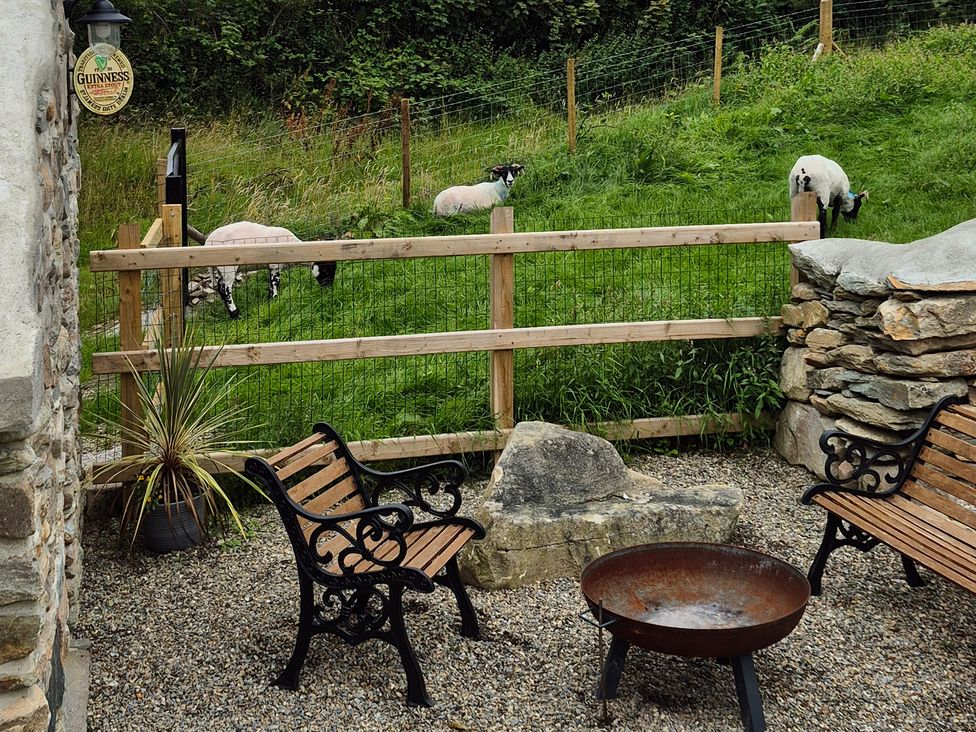 An outdoor seating area with benches and a fire pit at Annie’s Farm Cottage near Londonderry, Northern Ireland