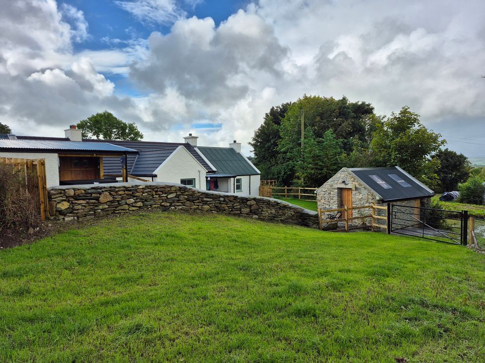 An outdoor area featuring a cottage and stone wall at Annie’s Farm Cottage near Londonderry, Northern Ireland
