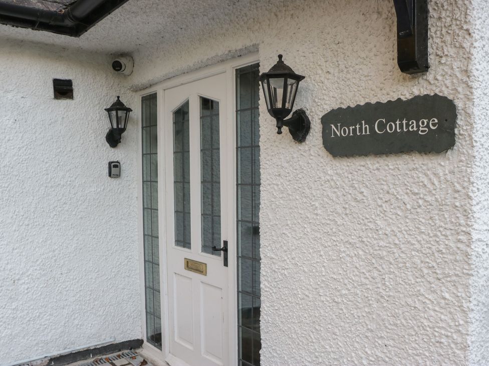 An entrance with a door and light fixtures at North Cottage in Bowness-On-Windermere