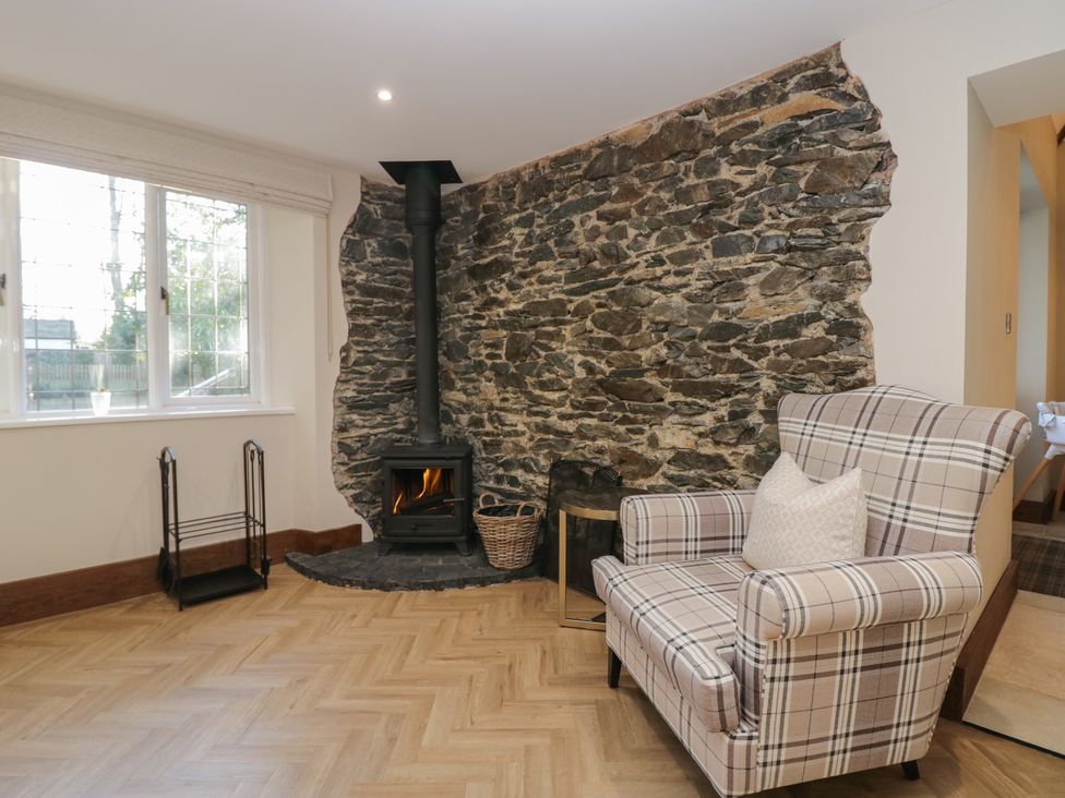 A living room with a fireplace and armchair at North Cottage in Bowness-On-Windermere