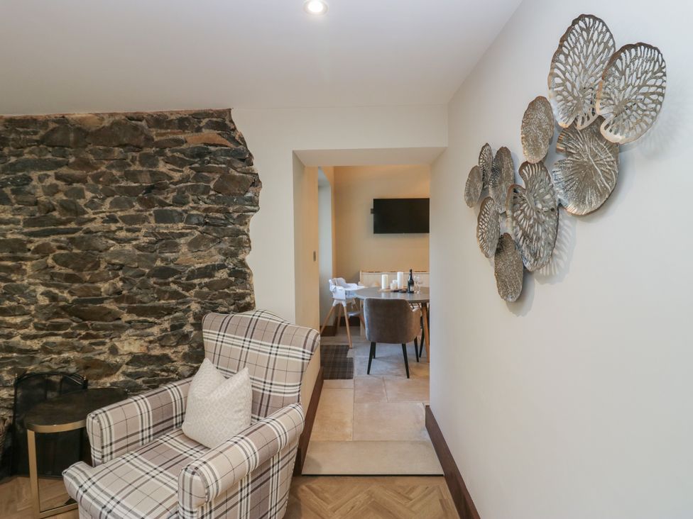 A living room with an armchair and decorative wall art at North Cottage in Bowness-On-Windermere