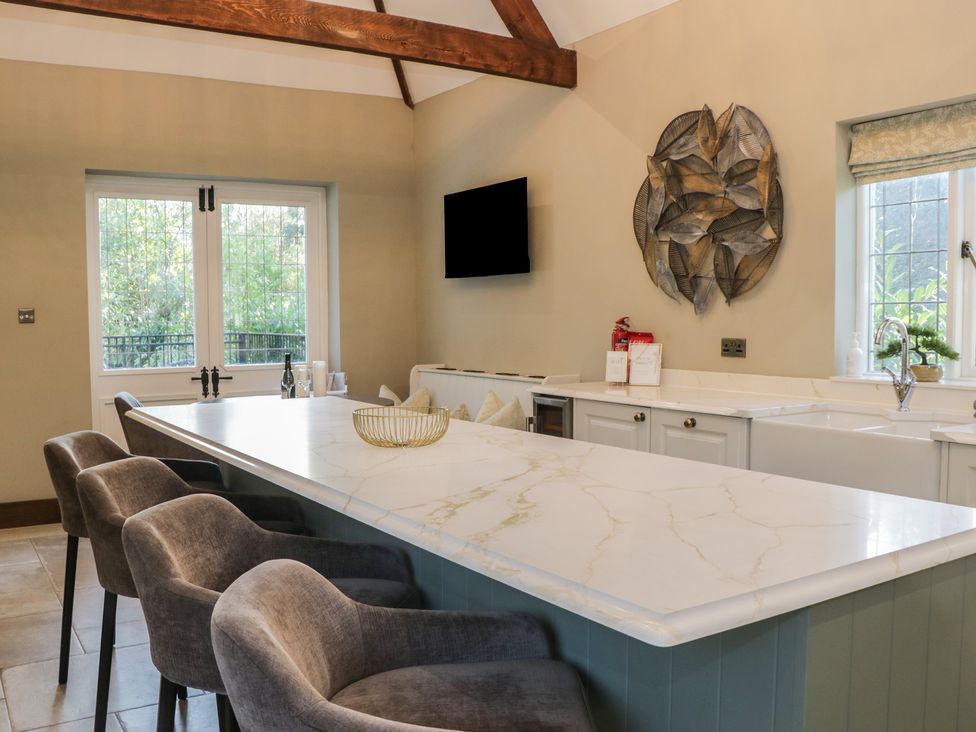 A kitchen with a large island and bar stools at North Cottage Bowness-On-Windermere
