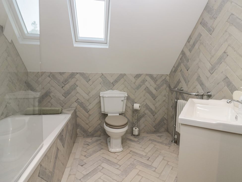 A bathroom with a toilet, bathtub, and sink at North Cottage in Bowness-On-Windermere
