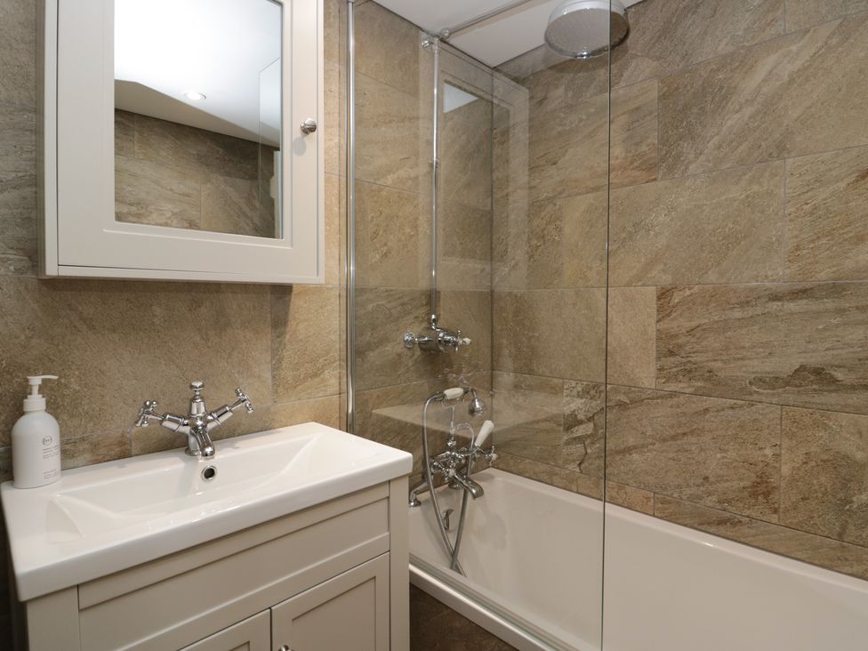 A bathroom featuring a bathtub with shower and a sink at North Cottage Bowness-On-Windermere