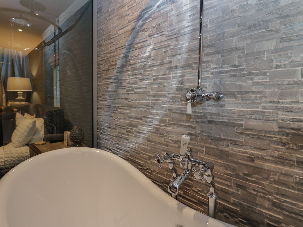 A bathroom featuring a bathtub and stone wall at North Cottage Bowness-On-Windermere