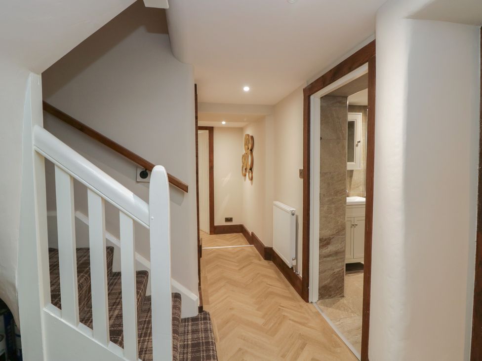 A hallway with staircase and door leading to a bathroom at North Cottage in Bowness-On-Windermere