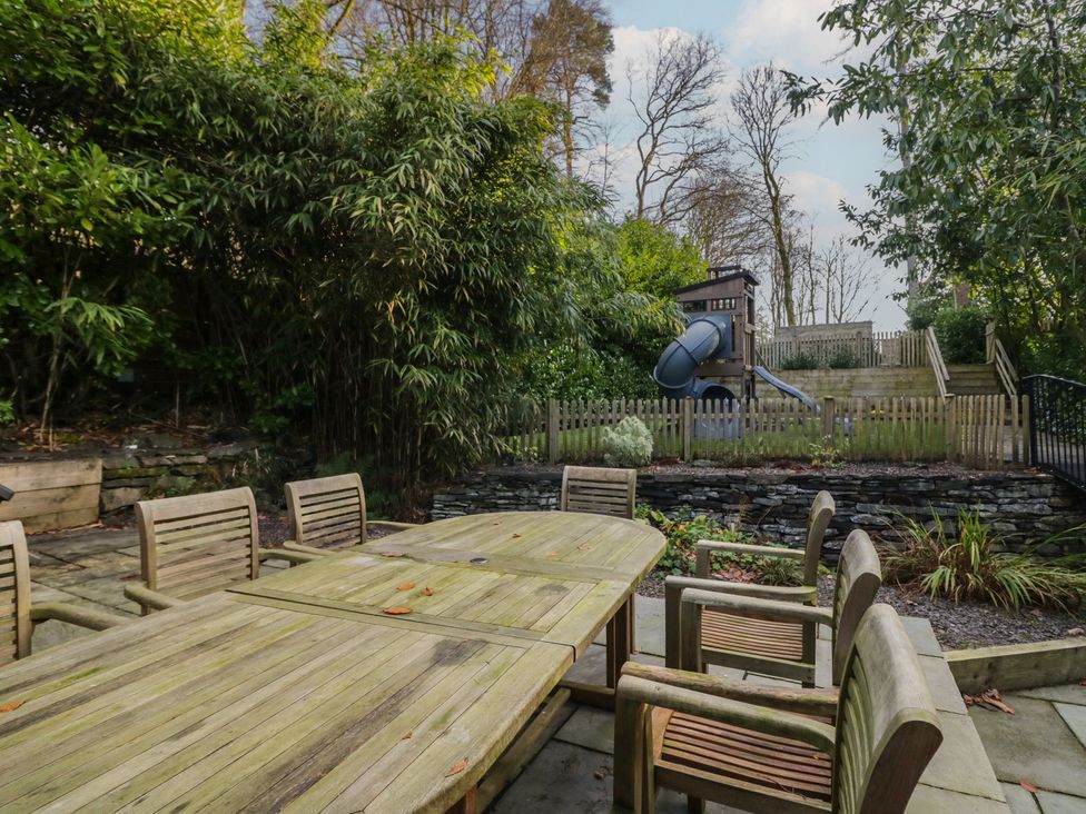 A garden with wooden furniture and a play area at North Cottage in Bowness-On-Windermere