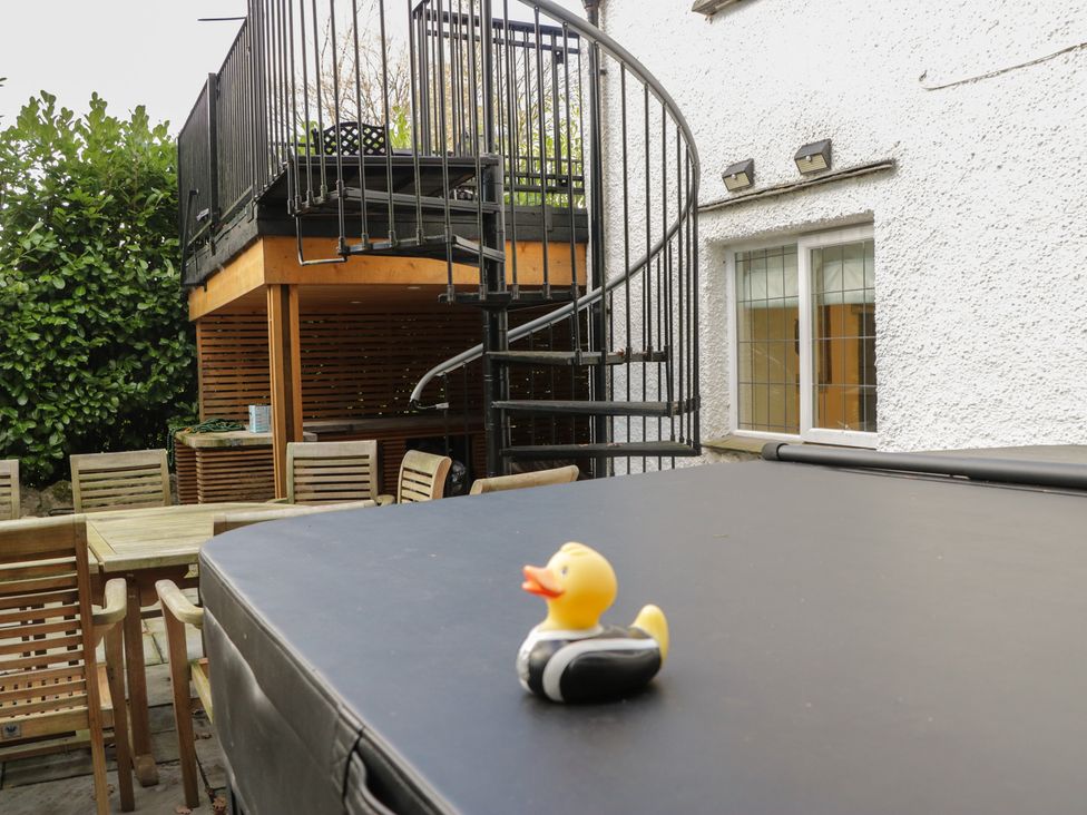 A dining area with a hot tub cover and spiral staircase at North Cottage in Bowness-On-Windermere
