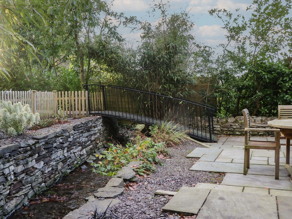 A garden with a bridge over a stream at North Cottage Bowness-On-Windermere