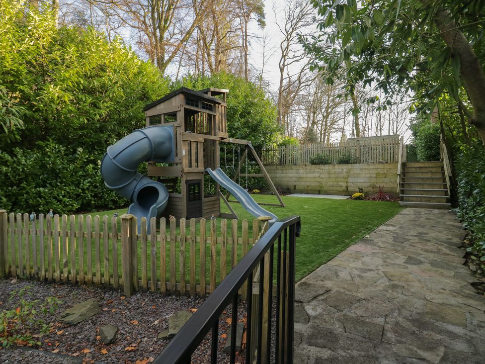 A garden with a playset and slide at North Cottage in Bowness-On-Windermere