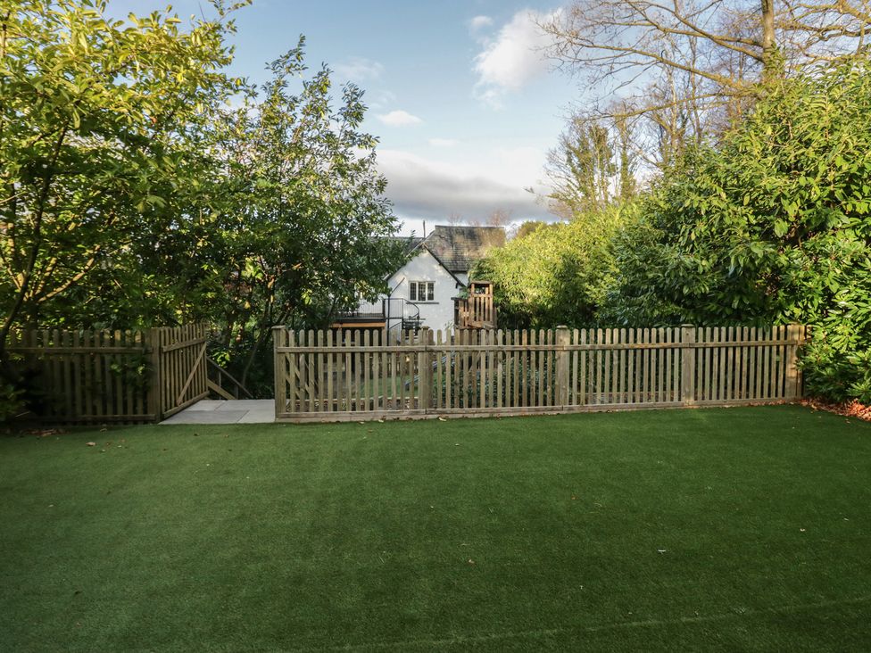 A garden with a fence and play structure at North Cottage in Bowness-On-Windermere