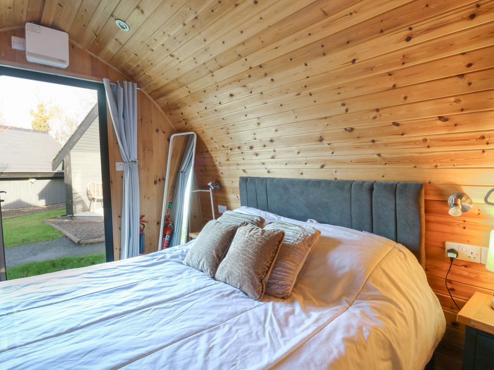 A bedroom with a bed and mirror at Garden Lodge 4 in Swansea