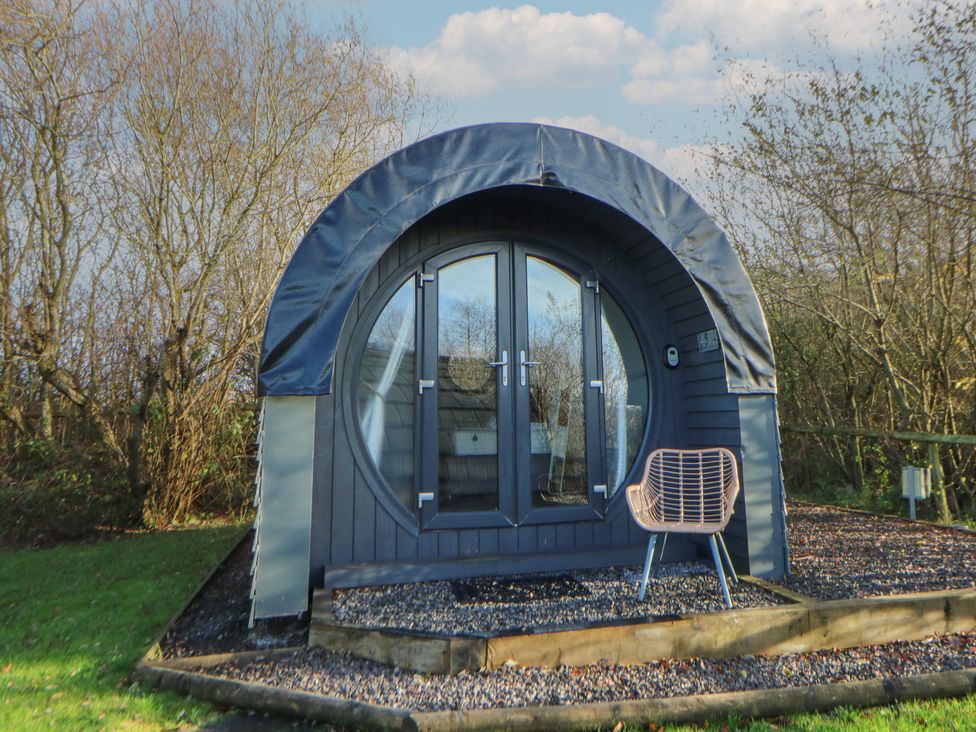 A glamping pod with double doors and a chair at Garden Lodge 5 Swansea