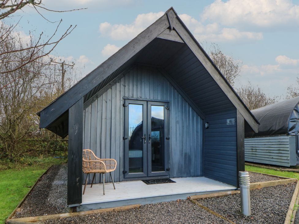 A cabin with an entrance door and chair at Garden Lodge 6 in Swansea