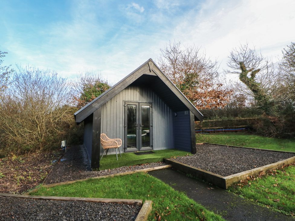 A cabin with a chair and pathway at Garden Lodge 8 in Swansea