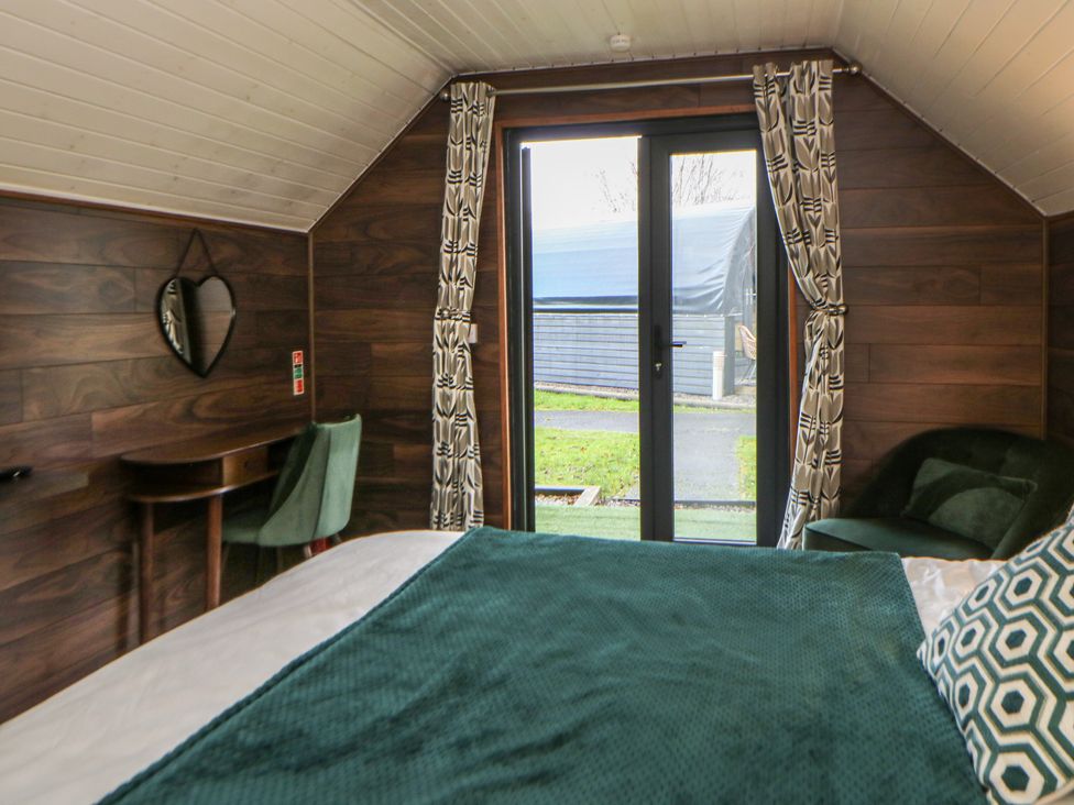 A bedroom with a bed and a mirror at Garden Lodge 8 in Swansea