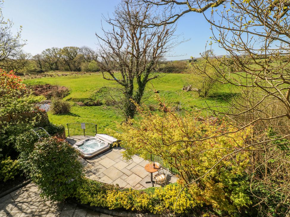 An outdoor area with a hot tub and a table with chairs at Rose Apartment Old Walls, Llanrhidian, Gower