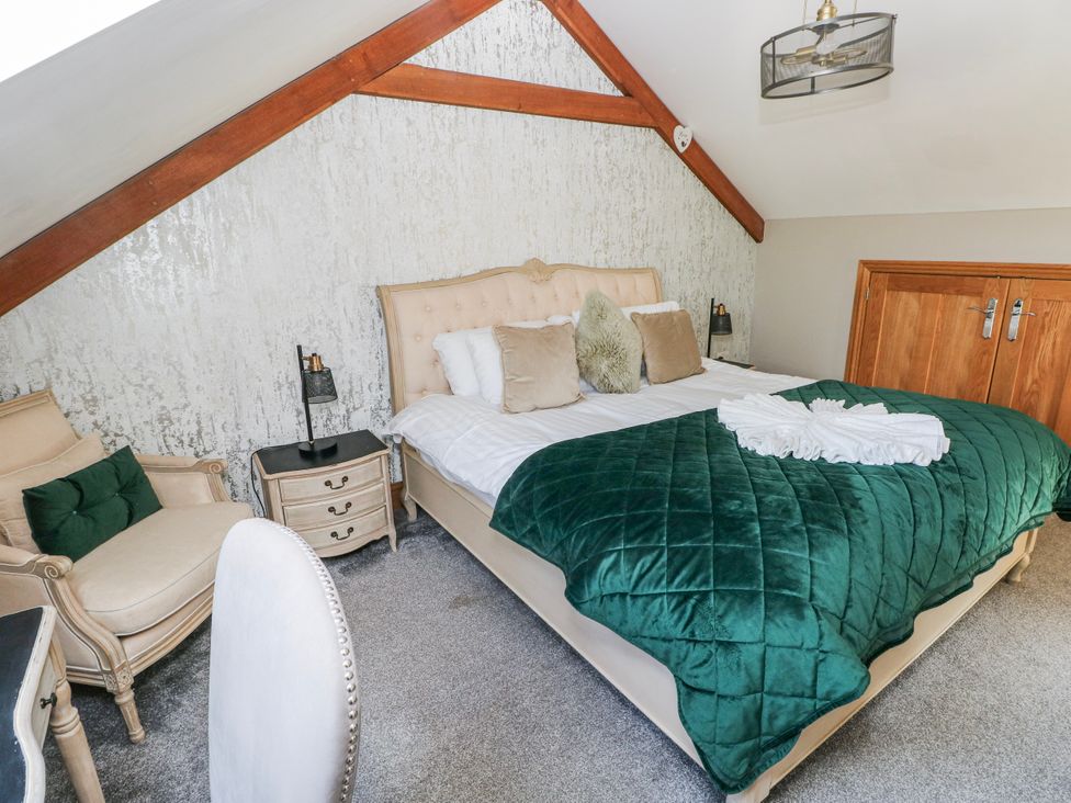 A bedroom with a bed and armchair at Rose Apartment in Old Walls, Llanrhidian, Gower