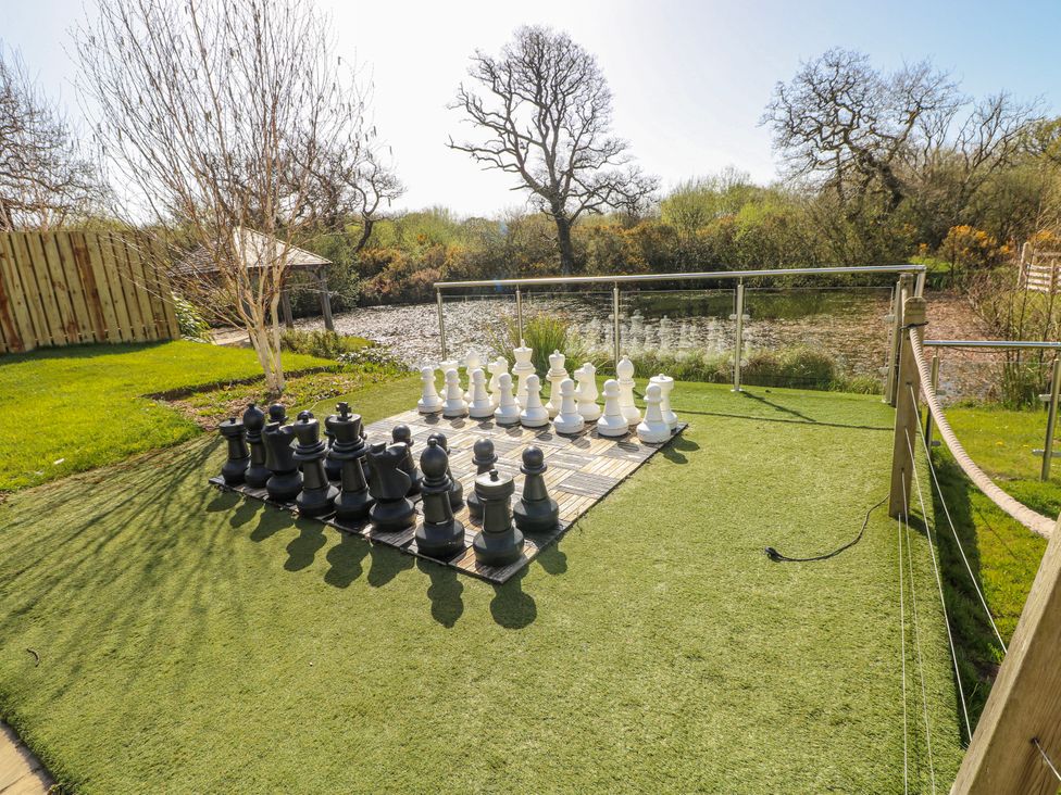 A garden with a large chess set next to a pond at Rose Apartment, Old Walls, Llanrhidian, Gower