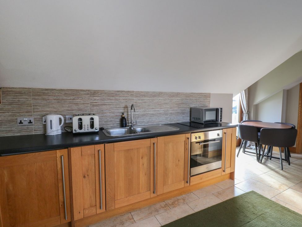 A kitchen with wooden cabinets and appliances at Willow Apartment in Swansea