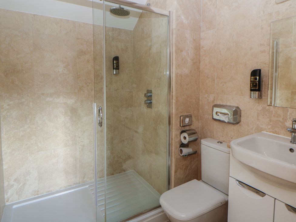 A bathroom with a shower, toilet, and sink at Willow Apartment in Swansea