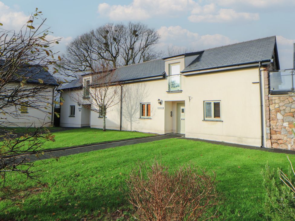 A house with windows and a door surrounded by grass and trees at Willow Apartment in Swansea