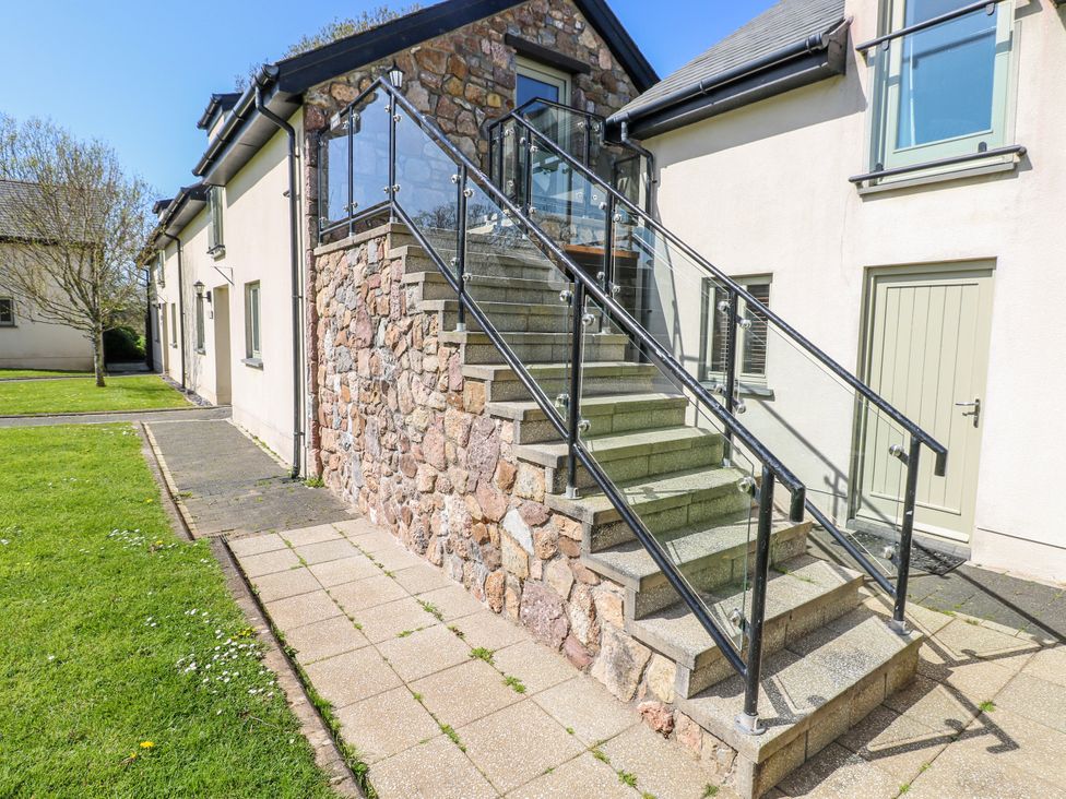 Stairs with glass railing leading to a door at Willow Apartment in Oldwalls, Llanrhidian, Gower