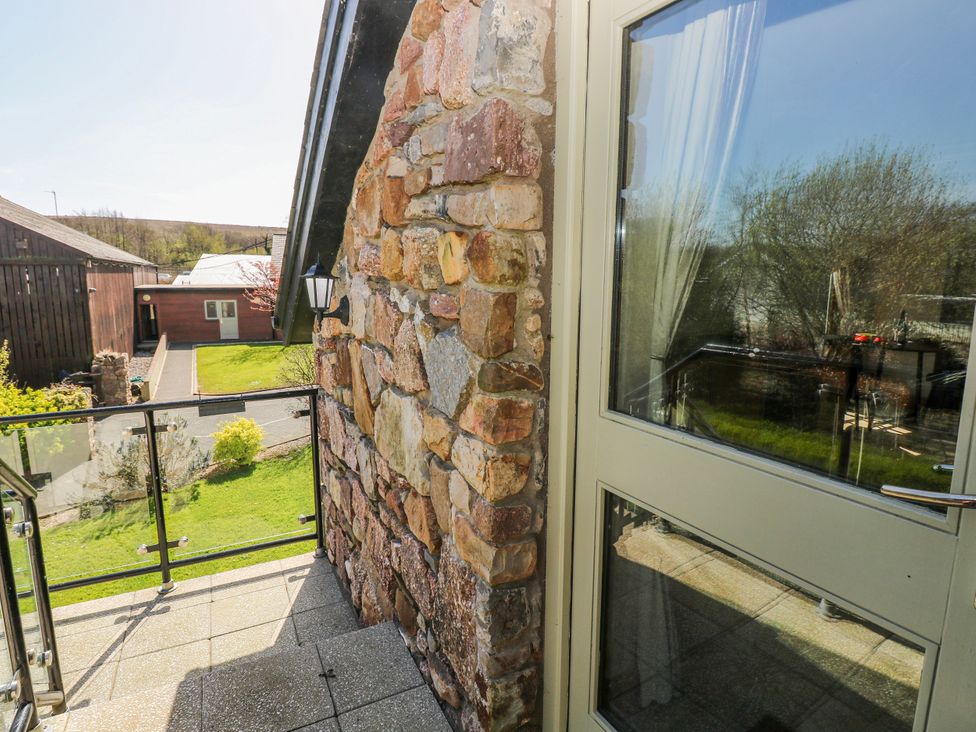 An outdoor area with a stone wall and glass railing at Willow Apartment in Oldwalls, Llanrhidian, Gower
