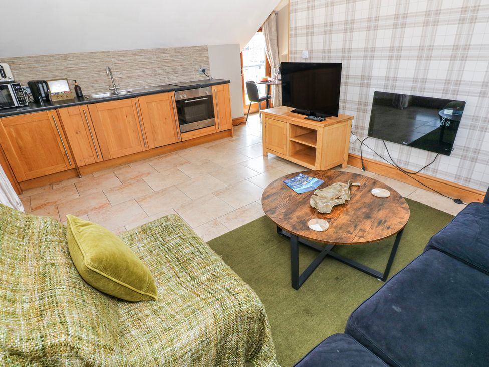 A living room with a kitchen area and a coffee table at Willow Apartment in Oldwalls, Llanrhidian, Gower
